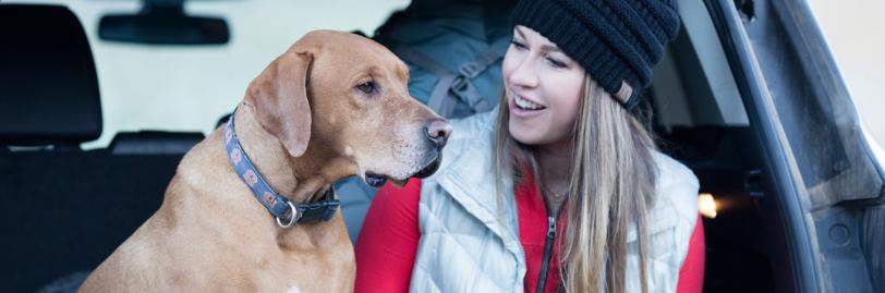 A woman and a dog sitting in the trunk of a car. 