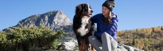 A woman sitting on a rock with a dog