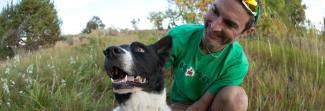 A man hugging a dog in a field of grass