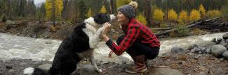 A woman and a dog next to each other by a river