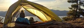 A woman and her dog sitting inside of a tent. 